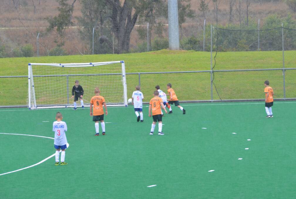 BRAVING THE WET: Australia versing England in the under 9s game before the midday washout caused delays.
