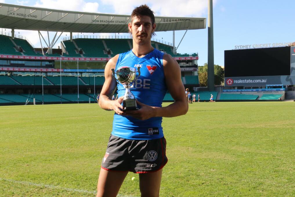 Sydney Swans player Sam Naismith holds the cup named in his honour.