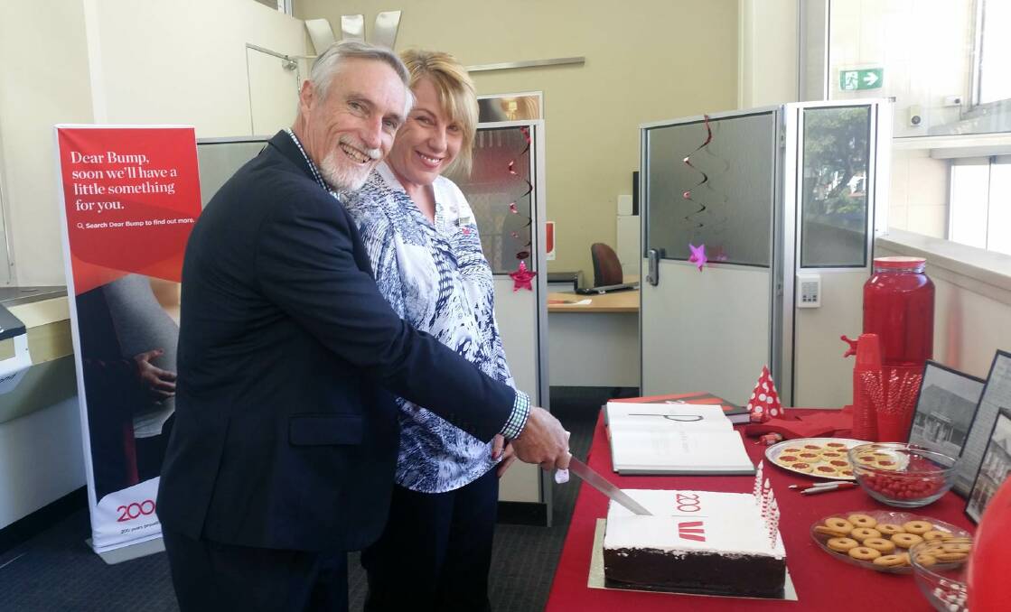 Mayor Paul Harmon cuts the cake with Westpac Inverell's longest-serving employee, Julie Hoscher.