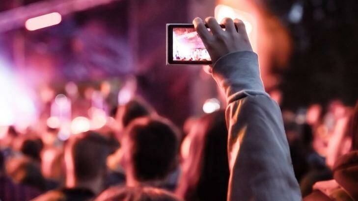 Recording video your with smartphone can stop others enjoying the event. Photo: 123rf.com