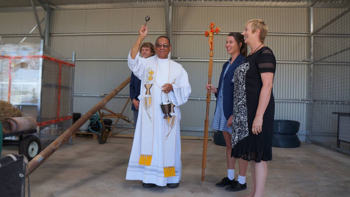 HOLY: Father Joe casts holy water in the new sheds to bless the facilities with student leaders Joe Smith, Mikayla Dal Santo and principal, Val Thomas.