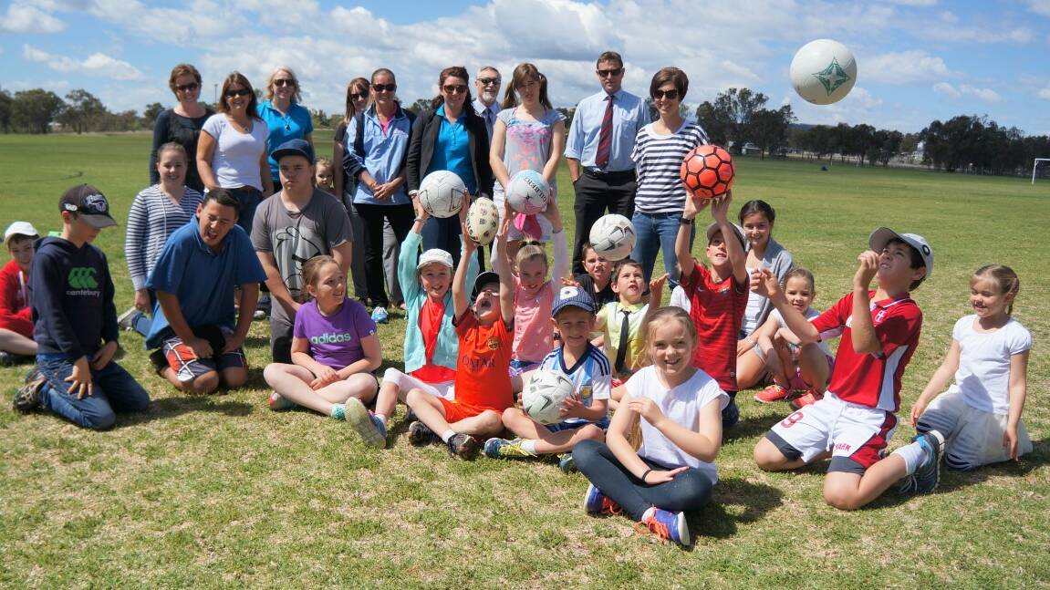 Adults, including Inverell mayor Paul Harmon are encircled by children at the Inverell Sporting Complex.