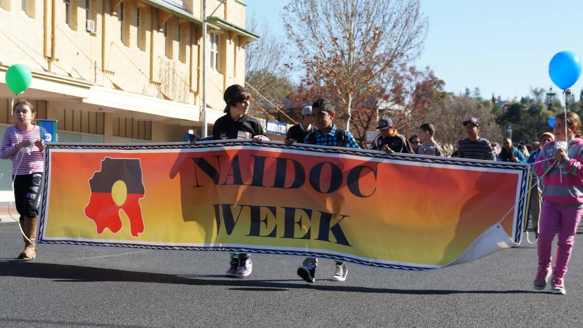Local children carry the NAIDOC banner in the 2014 Inverell NAIDOC Week march.
