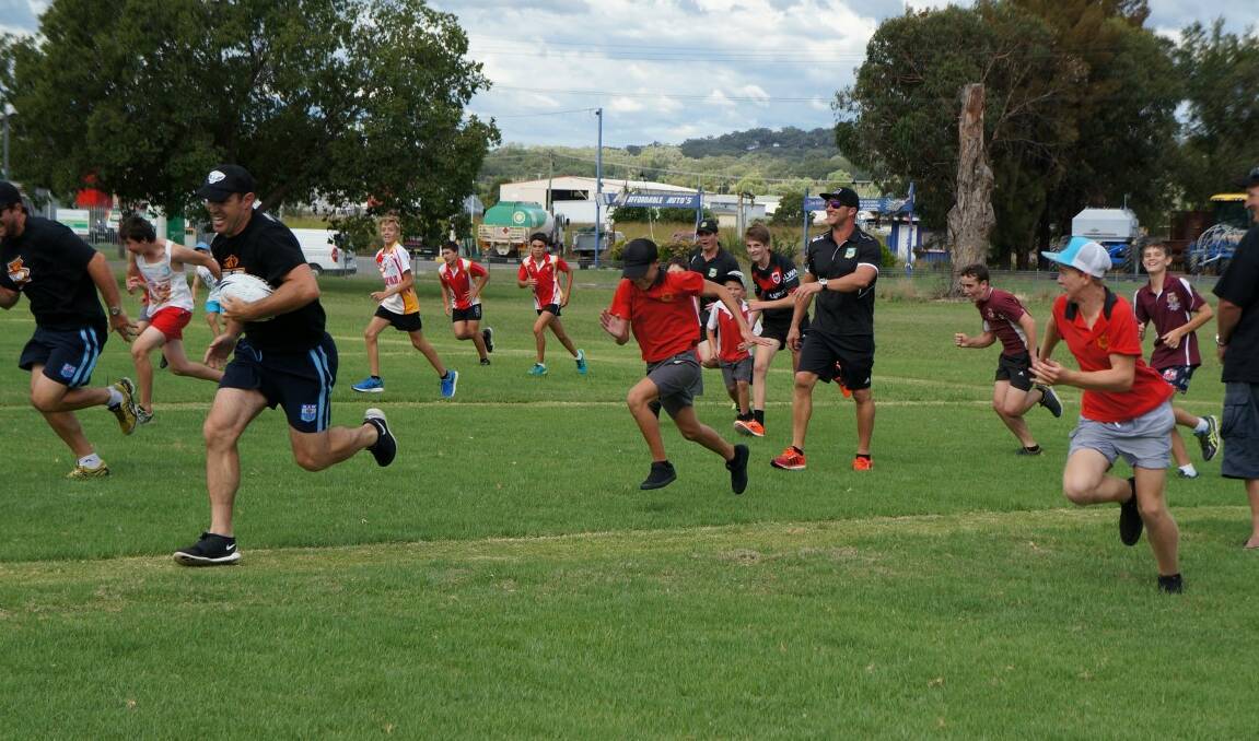 NRL star Brad Fittler leads a joyous herd of youngsters across the Kamilaroi Park field in Inverell.