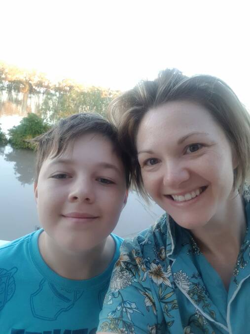 Leah Hancock with one of her sons, Cooper, as their home is surrounded by the flooding Mehi River.