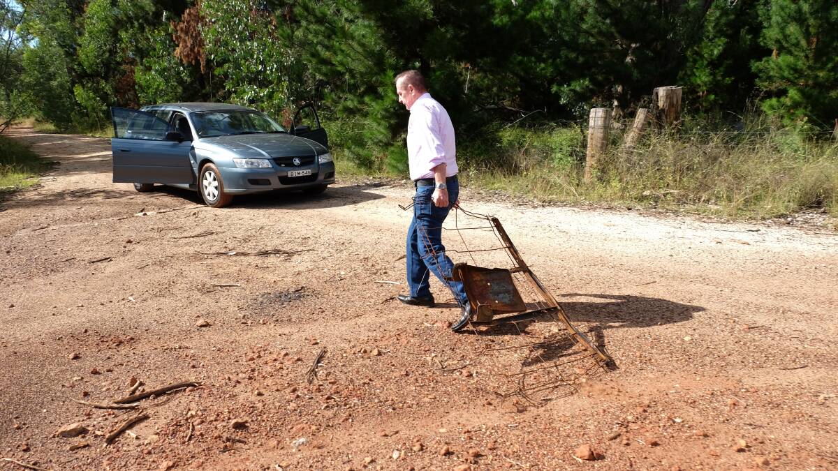 Peter Denovan drags the metal frame where a recent fire was lit in the middle of the plantation road. 