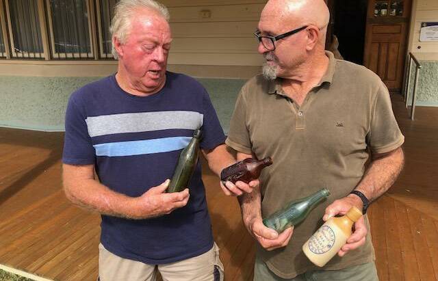 Robert Walburn and Peter Squires check out some of the rare historic bottles up for grabs. Robert holds tightly to the Holy Grail deep green Thomas bottle while
Peter displays the other Holy Grail, the blue label Egan ginger beer.

