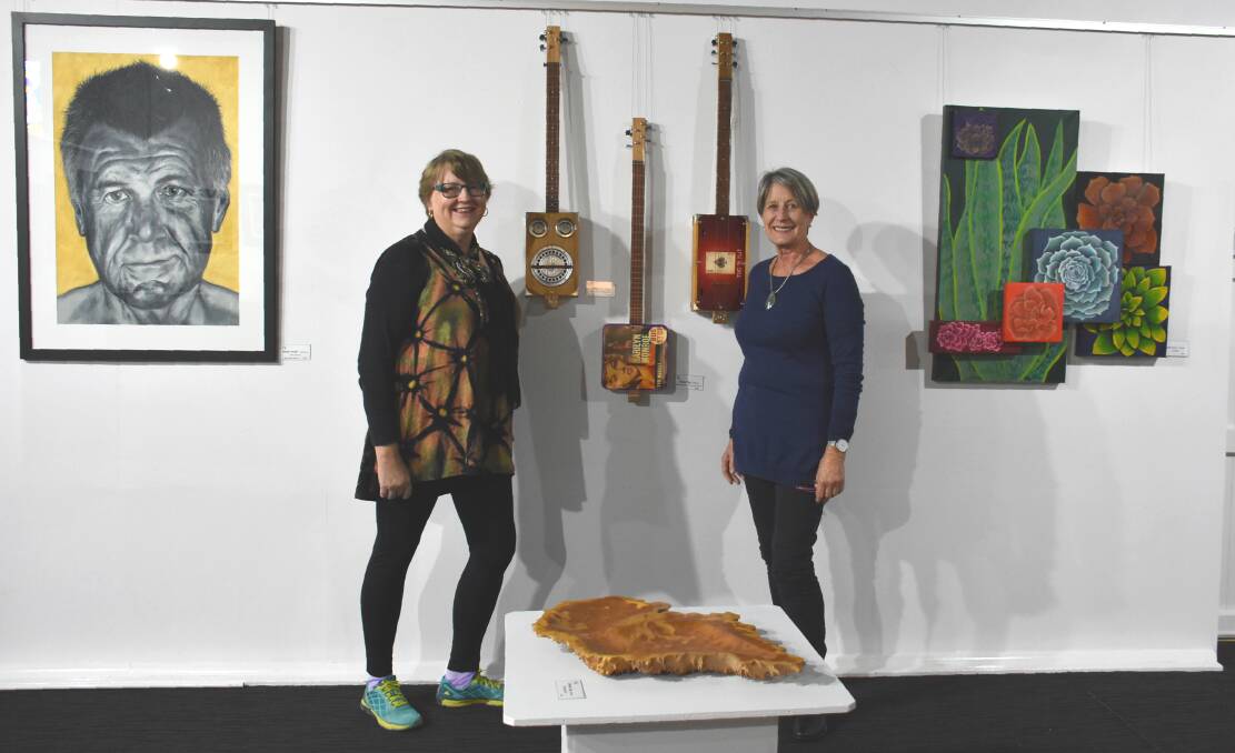 Exhibiting artists Leonie Turner and Carolyn McCosker with one of the more unique pieces, a set of ukuleles by Jeffrey Ting.