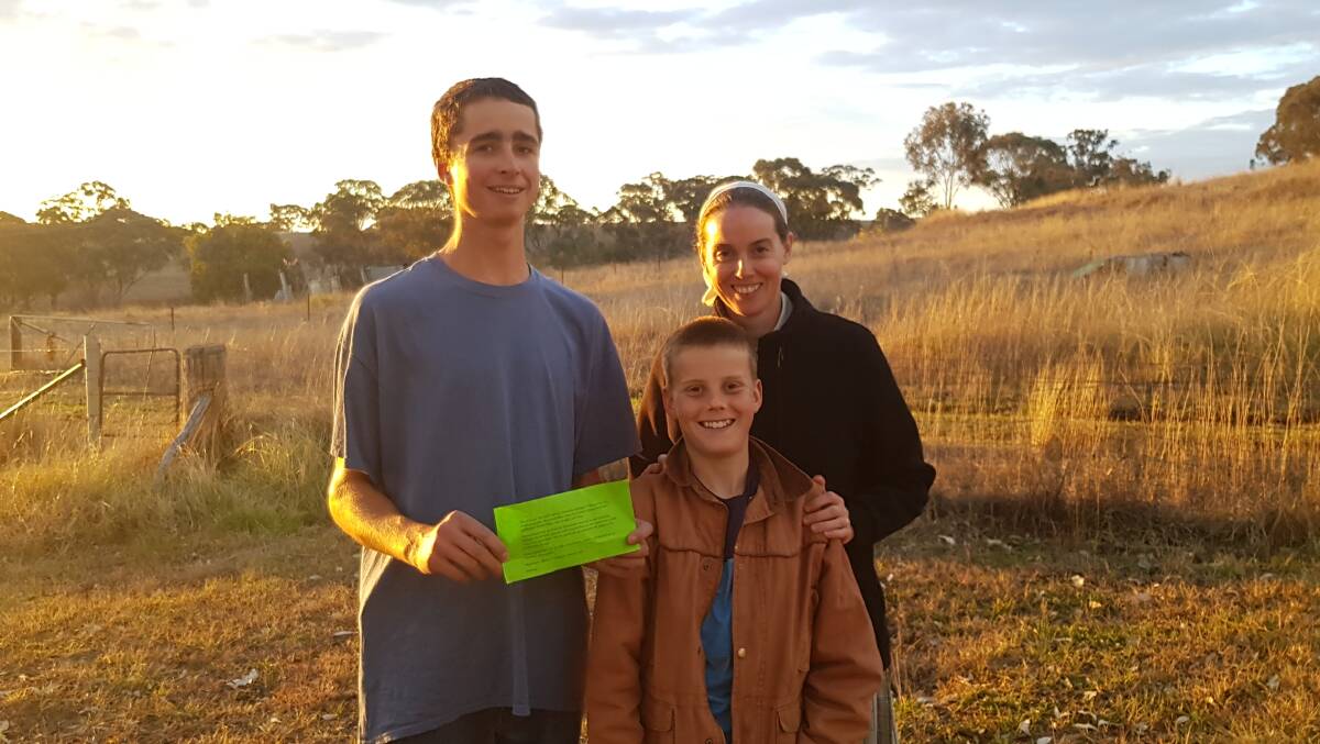 Brendan Koppschall, with Norann Voll and her son Derek, of Danthonia Bruderhof, holds the note of encouragement left by a Toowoomba couple. The community plans to 'pay it forward' to someone they feel is in more need. 