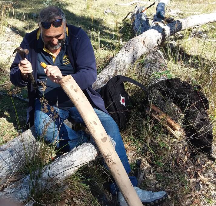 Workshop participant Lee Patterson from Guyra hollows out a branch to make a didgeridoo.