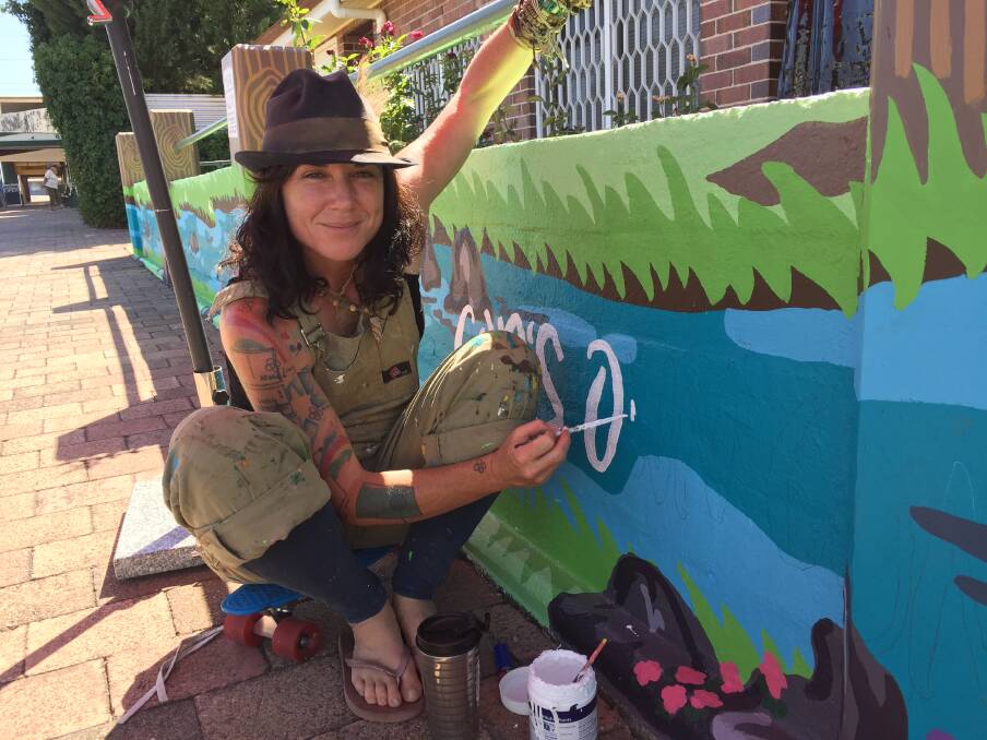 Kelly Jones works on a mural in front of the Ashford Post Office.
