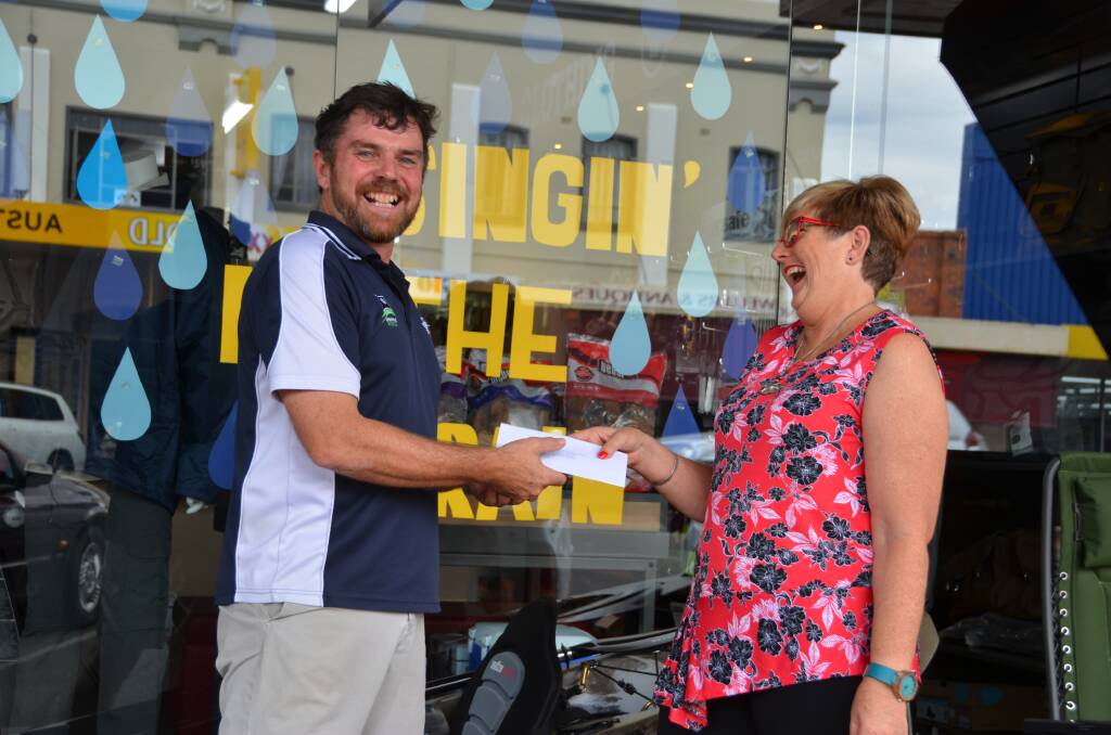 Compleat Angler & Camping World Inverell owner Greg Cannon gives a $50 gift voucher to expert rain dancer Lyn Hill. 