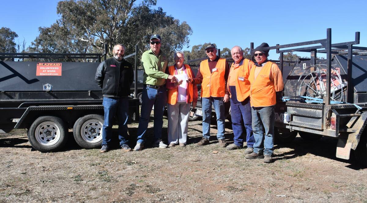 Disaster relief: 2NZ's James Monte Irvine and Bundarra's Peter Gregory hand over a cheque to busy BlazeAid members at the base camp on Friday.