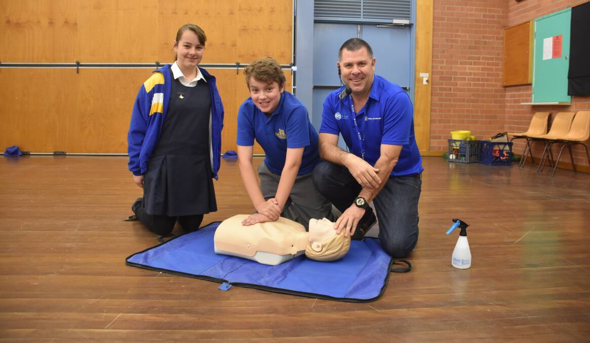 Ross Hill students Heidi Robinson and Bailey Martin learn a life-saving skill under the watchful eye of Cameron McFarlane.