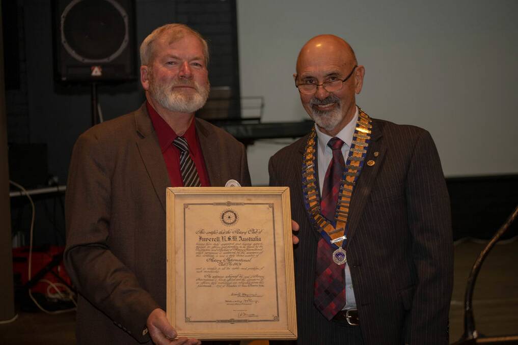 Incoming president Bruce George and outgoing president Neil Eigeland hold the Rotary Club of Inverell charter from 1936.