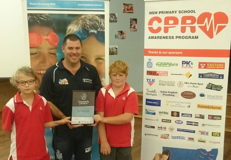 Cameron McFarlane (centre) presents a certificate to Inverell Public's Elexis Wilson and  Harry Edmonds.