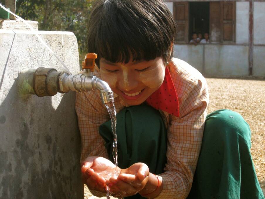 The tanks in Myanmar are partly funded by residents of Inverell, providing fresh, clean water to thousands who have gone without. A village child eagerly takes a handful to drink. Photo by Rosemary Breen.